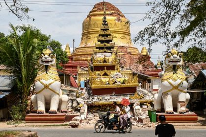 This photo taken on April 12, 2025 shows people driving past the debris of a damaged Buddha statue in Inwa on the outskirts of Mandalay, following the devastating March 28 earthquake.