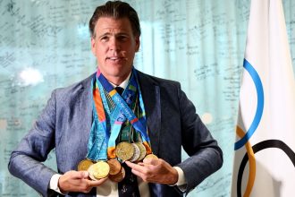 US swimmer Gary Hall Jr. poses wearing the replica Olympic medals that the IOC president to him during a handover ceremony after the originals were destroyed with his house in the Los Angeles wildfires earlier this year.