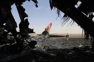 A Houthi rebel walks next to a destroyed plane at the Sanaa International Airport on Wednesday, a day after Israel's military warplanes struck Yemen's rebel-held capital Sanaa.