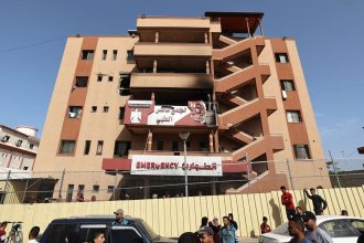 People and traffic pass the fence of the Nasser hospital in Khan Younis, which was hit in an Israeli strike at dawn that targeted the southern Gaza Strip city on Tuesday.