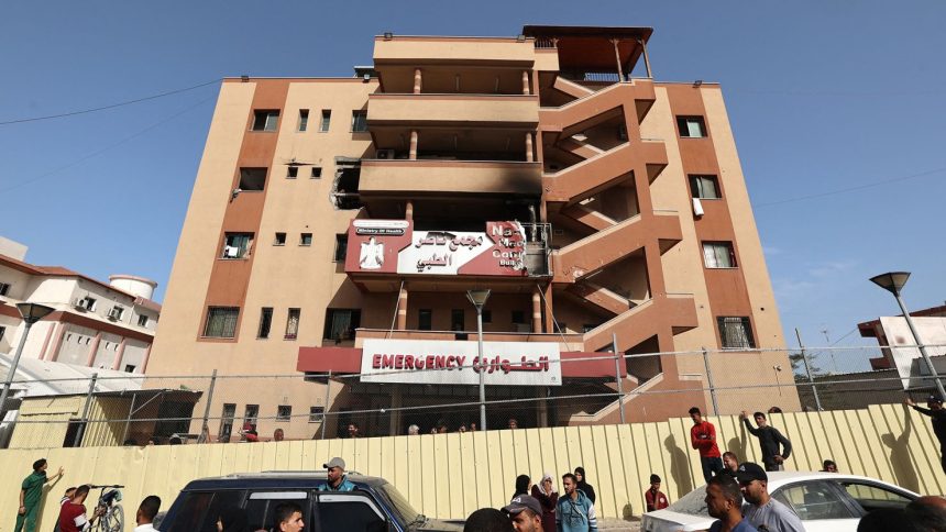 People and traffic pass the fence of the Nasser hospital in Khan Younis, which was hit in an Israeli strike at dawn that targeted the southern Gaza Strip city on Tuesday.