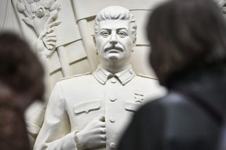 Commuters pause in front of the newly unveiled high relief depicting Soviet dictator Joseph Stalin in a passage at Moscow's Taganskaya subway station on May 15, 2025.