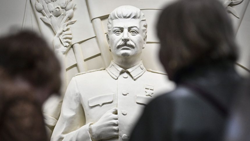 Commuters pause in front of the newly unveiled high relief depicting Soviet dictator Joseph Stalin in a passage at Moscow's Taganskaya subway station on May 15, 2025.