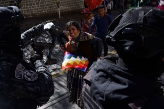 A supporter of Bolivia's former president Evo Morales confronts riot police, as Morales supporters attempt to reach the Supreme Electoral Tribunal to demand his registration as a presidential candidate in La Paz, Bolivia, on Friday.