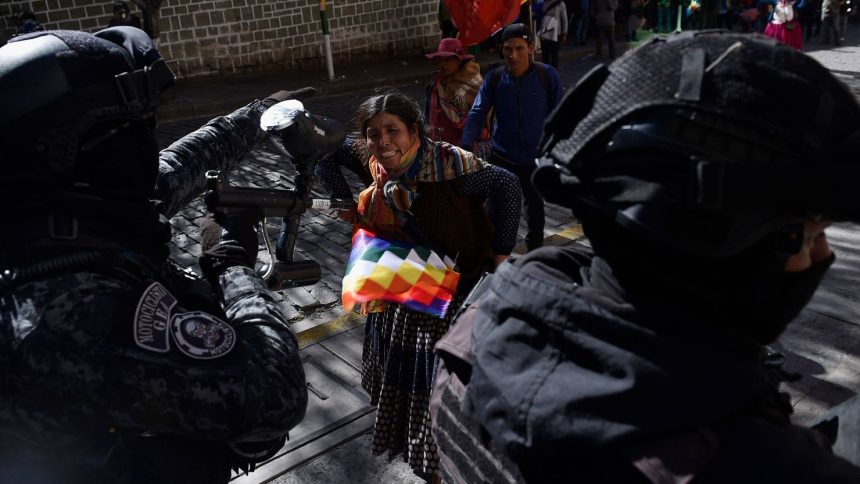 A supporter of Bolivia's former president Evo Morales confronts riot police, as Morales supporters attempt to reach the Supreme Electoral Tribunal to demand his registration as a presidential candidate in La Paz, Bolivia, on Friday.