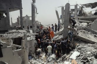 Crowds gather atop the ruins of residential buildings as search and rescue teams continue efforts in Gaza, on Saturday.