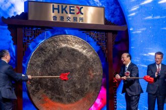 Robin Zeng, founder and chairman of Contemporary Amperex Technology (CATL), strikes a gong as Paul Chan, Hong Kong's financial secretary, and Bonnie Chan, CEO of Hong Kong Exchange, applaud during the CATL listing ceremony at the Hong Kong Stock Exchange on Tuesday.
