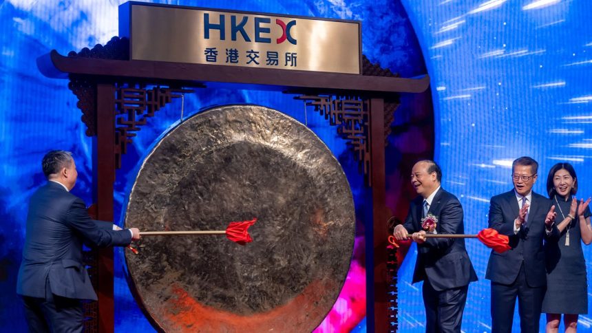 Robin Zeng, founder and chairman of Contemporary Amperex Technology (CATL), strikes a gong as Paul Chan, Hong Kong's financial secretary, and Bonnie Chan, CEO of Hong Kong Exchange, applaud during the CATL listing ceremony at the Hong Kong Stock Exchange on Tuesday.