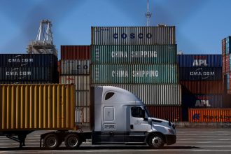 A truck drives by stacked shipping containers at the Port of Oakland on May 20 in Oakland, California. The Port of Oakland saw a 14.7% decrease in overall cargo volume in April after the Trump administration's tariffs were enacted.