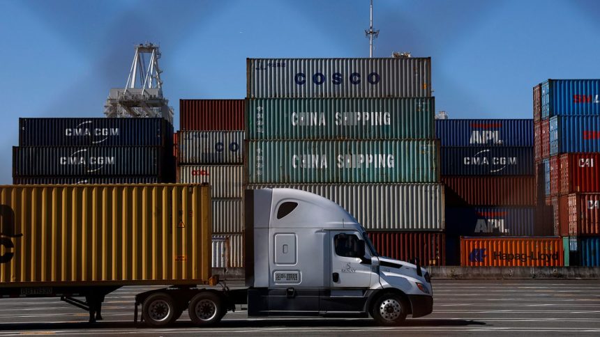 A truck drives by stacked shipping containers at the Port of Oakland on May 20 in Oakland, California. The Port of Oakland saw a 14.7% decrease in overall cargo volume in April after the Trump administration's tariffs were enacted.