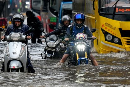 Commuters wade through a flooded street after heavy rain showers in Mumbai on May 26.
