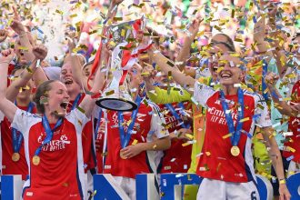 Kim Little (left) and Leah Williamson (right) lift the Women's Champions League trophy after their win.