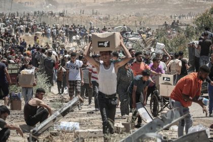 Palestinians carry boxes of humanitarian aid collected from a distribution center in the Netzarim Corridor, central Gaza Strip, on Thursday.