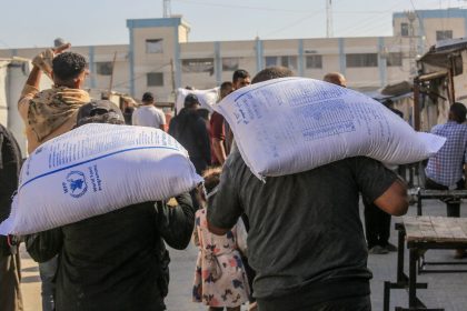 People carry sacks of flour distributed by charities in Khan Younis on Saturday.