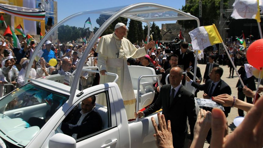 Pope Francis waves to the crowd, from his popemobile, as he arrives at the Manger Square for an open-air mass on May 25, 2014, outside the Church of the Nativity in Bethlehem, in the occupied West Bank.