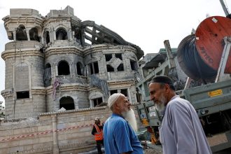 Men walk after missiles fired from Iran impacted a residential building in Tamra, northern Israel, June 15, 2025.