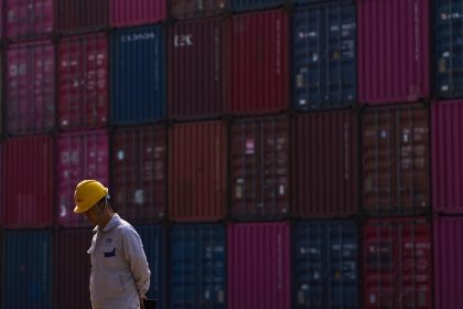 A worker walks by containers at Yangluo Port on the Yangtze River in Wuhan, central China's Hubei Province, on May 23, 2025.