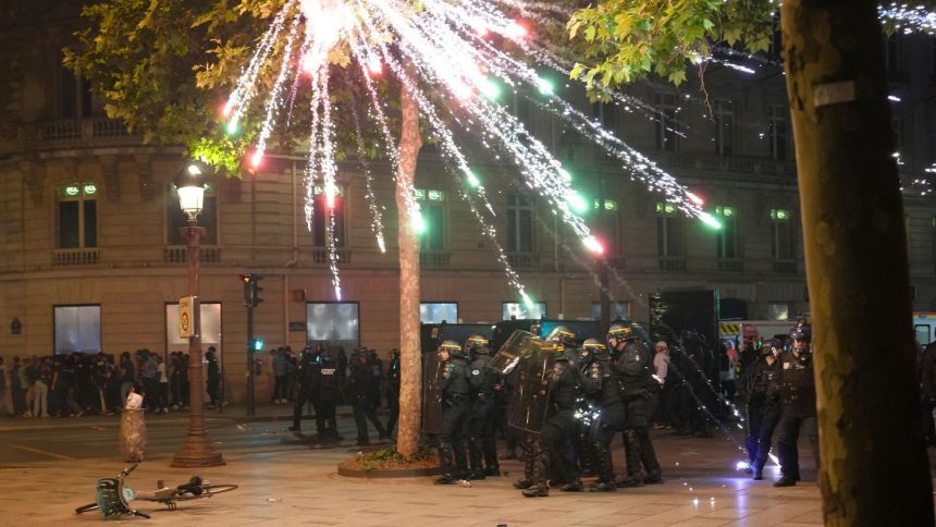 Fireworks explode over riot police officers on the Champs-Elysees in Paris.