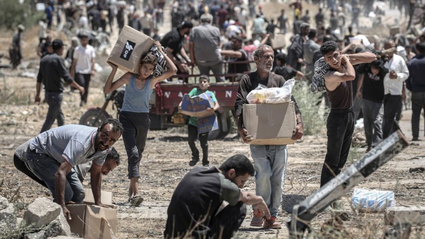 Palestinians move boxes of humanitarian aid collected from a distribution center in the Netzarim Corridor, central Gaza Strip, on May 29.