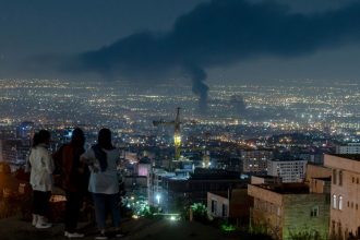 People gather on a hill to watch smoke rising in the distance from an Israeli airstrike in Tehran, Iran, on June 14, 2025. Iran's foreign minister said the country would respond "decisively and proportionally" to a wave of attacks that Israel launched beginning in the early hours of June 13. The attacks targeted multiple military, scientific and residential locations, as well as senior government officials.