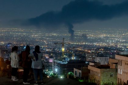 People gather on a hill to watch smoke rising in the distance from an Israeli airstrike in Tehran, Iran, on June 14, 2025. Iran's foreign minister said the country would respond "decisively and proportionally" to a wave of attacks that Israel launched beginning in the early hours of June 13. The attacks targeted multiple military, scientific and residential locations, as well as senior government officials.