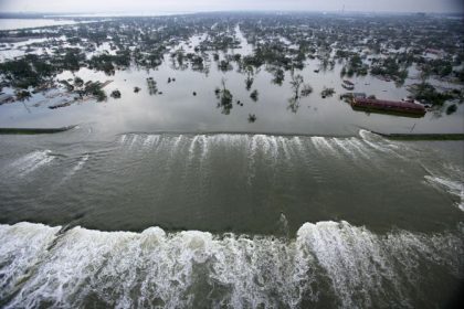 Water spills over a levee along the Inner Harbor Navigational Canal in the aftermath of Hurricane Katrina on August 30, 2005, in New Orleans. Katrina struck the Gulf Coast on August 29, 2005. After levees and flood walls protecting New Orleans failed, much of the city was underwater.